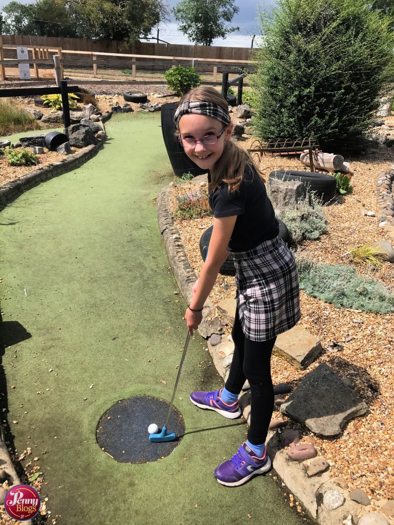 A ten year old girl posing on teh crazy golf course at Woodside Animal Farm