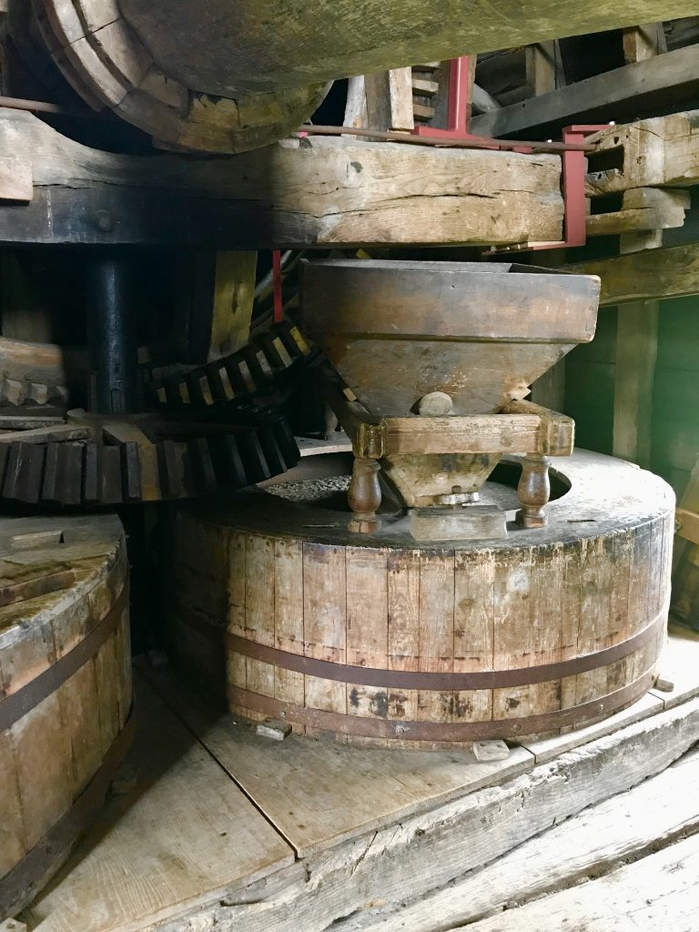 One of teh milling stones inside the windmill with a wooden surround.