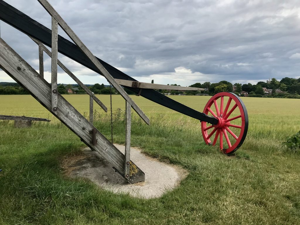 The stairs leading up into the windmill and a wooden arm with a red wheel, looking a bit like a cart wheel on the end of it.