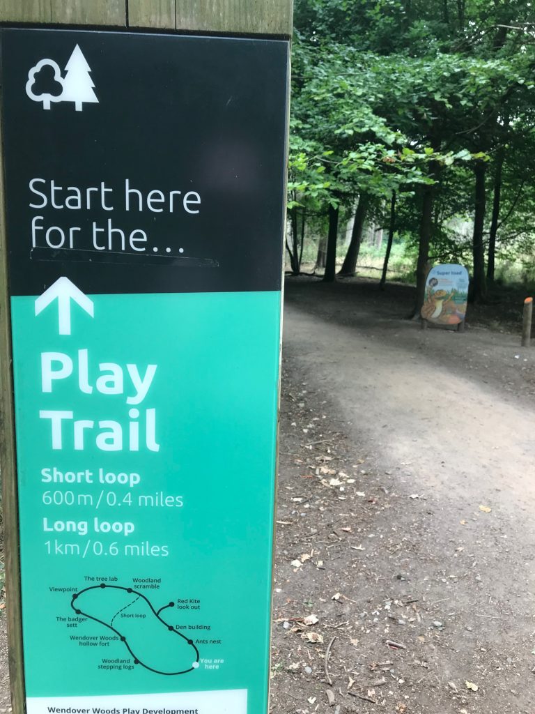 In the left foreground of the picture is a sign showing the start of the Play Trail at Wendover Woods, including a plan of the trail showing the long and short routes. In the distance on the right of the picture is a path leading into the woods and you can see another sign - which is part of the Superworm trail.
