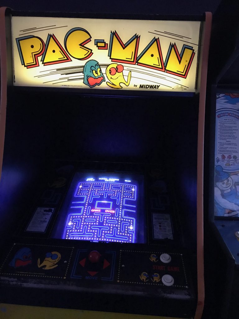 A picture of a vintage Pac-Man arcade game. The screen is showing game over.