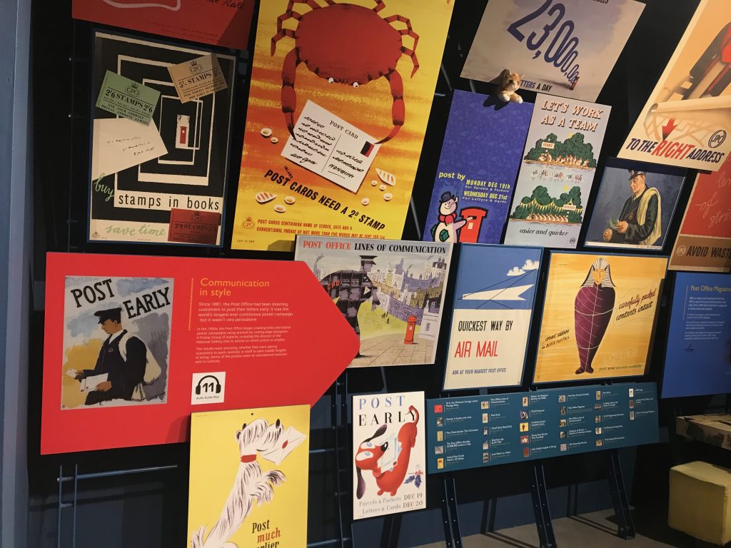 A display showing a variety of old Post Office and Royal Mail advertising posters at the Postal Museum.