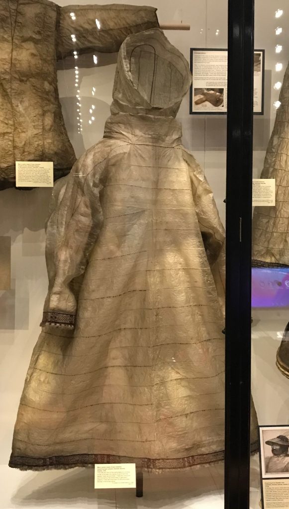 A museum display case showing off the parka that I have described. It has a hood and is of a relatively simple shape with arms. It looks like it more practical than decorative from a distance.