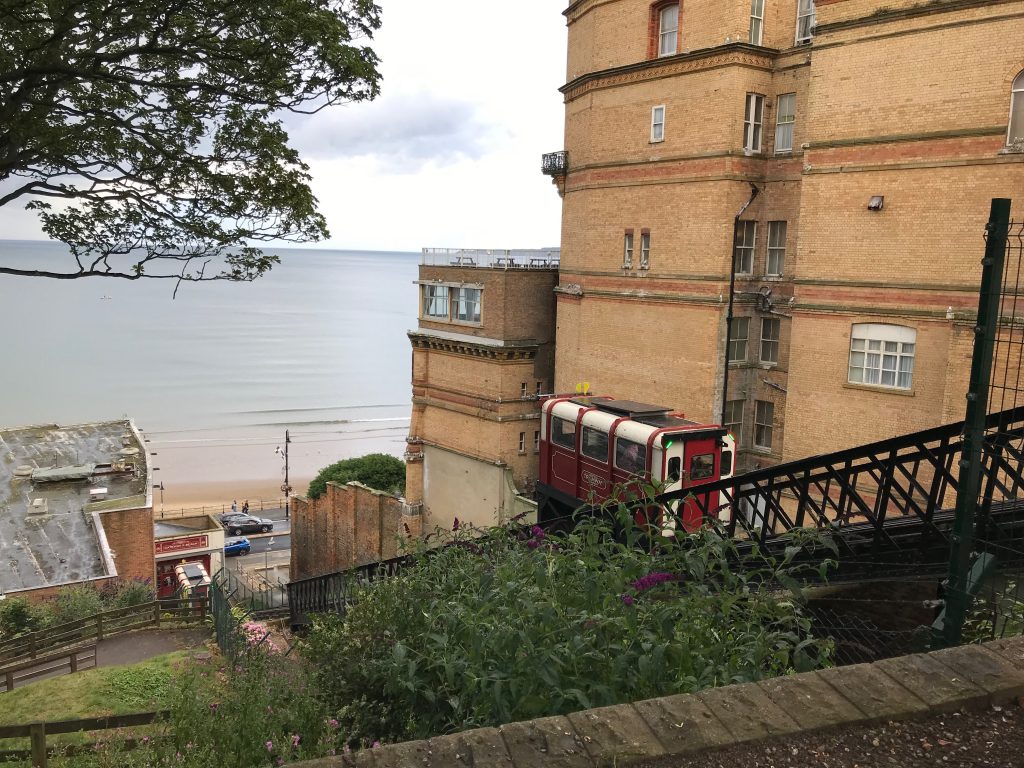 A picture of one of the tramcars half way down the tracks and the second car visible just starting its ascent. The bottom station and the sea can be seen in the background.