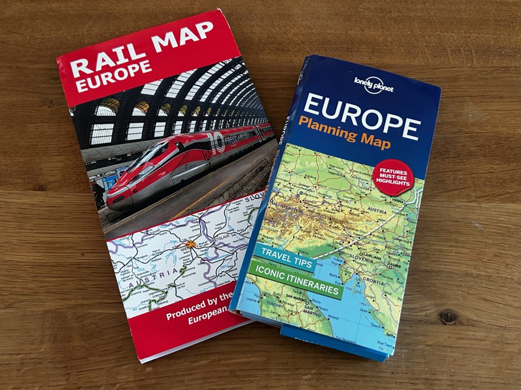 A pictures showing two maps laid closed on a wooden table. On the left is the Rail Map Europe. On the right the Lonely Planet Europe Planning Map.